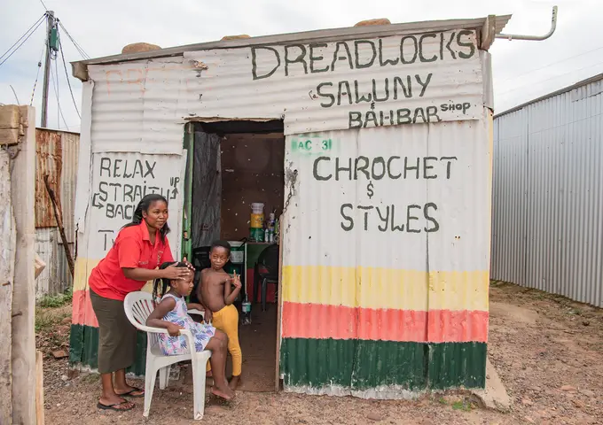 Hairdresser Portia doing Pretty's hair with Luva looking on. Railton, Swellendam. 2020